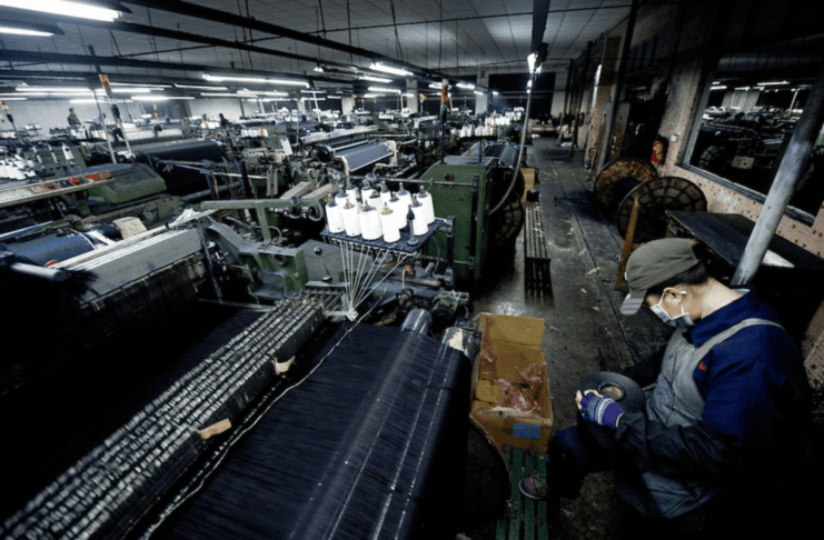Xintang, the Blue Jeans City. A worker supervises a power loom weaving denim to be used to manufacture blue jeans in LSH textile company, in Xintang, Guangdong province, China, on February 9, 2012. Photo by Lucas Schifres/Pictobank. Public Domain.