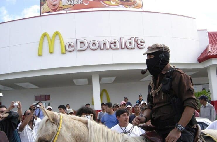 EZLN: Marcos og McDonald's. Den "uddelegerede Zero" med hest og pibe passerer en McDonalds i Playa del Carmen, Mexico. Frokost-spisende beboere fik et ekstra show. Foto: taget 16 januar 2006 af vcarera. (CC BY-NC-SA 2.0).