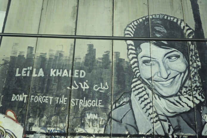 Mural with Leila Khaled, veteran and leading member of the PFLP, somewhere along the apartheidwall. Photo: Boris Kasimow. (CC BY 2.0).